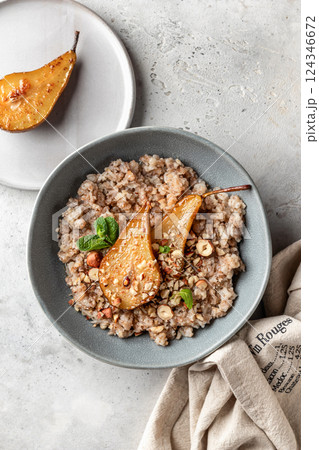 Wholegrain oatmeal porridge with caramelized pear, nuts and honey on white table, healthy food for breakfast Wholegrain oatmeal porridge with caramelized pear, nuts and honey on white table, healthy food for breakfast 124346672