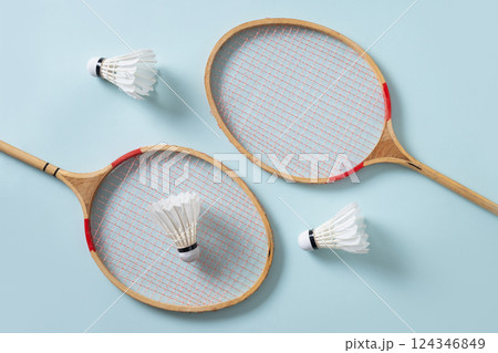 Two wooden badminton rackets and white feather badminton shuttlecocks on green background. View from above. Sport background. Concept racket sport. Leisure games. Two wooden badminton rackets and white feather badminton shuttlecocks on green background. View from above. Sport background. Concept racket sport. Leisure games. 124346849