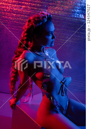 Woman poses with silver tape body art in lingerie under colorful lights 124347027