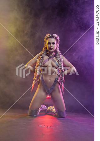 Woman in lingerie displays silver body art at a lively studio 124347065