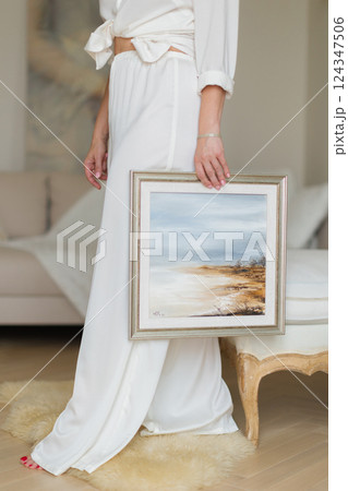 A woman is holding a beautiful painted picture in her hands. 124347506