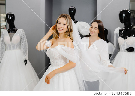 The bride-to-be chooses a dress for the wedding. A dressmaker's assistant is fitting a dress for the bride The bride-to-be chooses a dress for the wedding. A dressmaker's assistant is fitting a dress for the bride 124347599