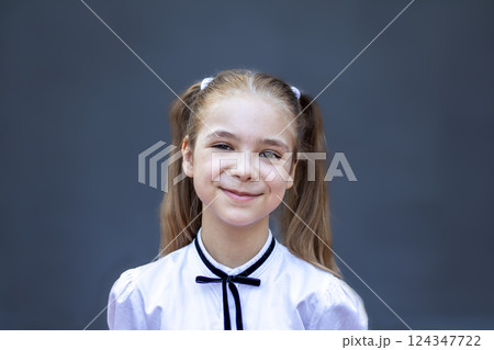 Smiling young girl with pigtails against a simple gray background Smiling young girl with pigtails against a simple gray background 124347722