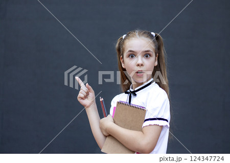 Young girl with notebook expressing surprise while pointing out new inspiration Young girl with notebook expressing surprise while pointing out new inspiration 124347724