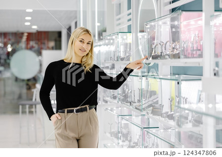 Woman choosing jewelry in a store pointing at glass display 124347806