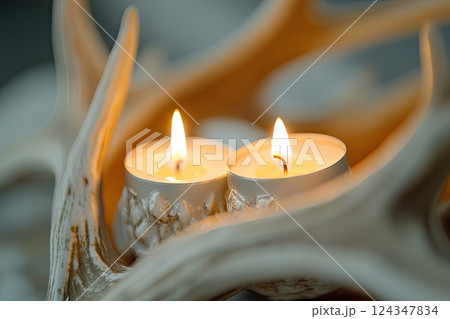 Close-up of a rustic antler candle holder with burning candles, creating a warm and cozy atmosphere. Close-up of a rustic antler candle holder with burning candles, creating a warm and cozy atmosphere. 124347834