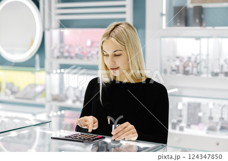 Jewelry store saleswoman calculating price using calculator 124347850