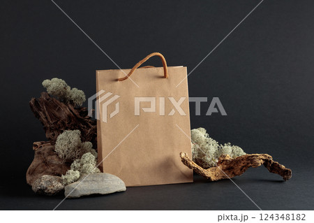 Paper bag with snags, stones, and moss on a black background. 124348182