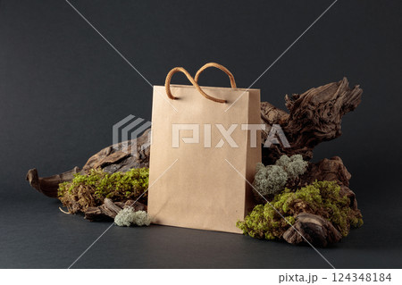 Paper bag with snags and moss on a black background. 124348184