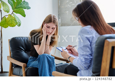 Sad upset young woman patient in therapy session in psychologist office 124348782
