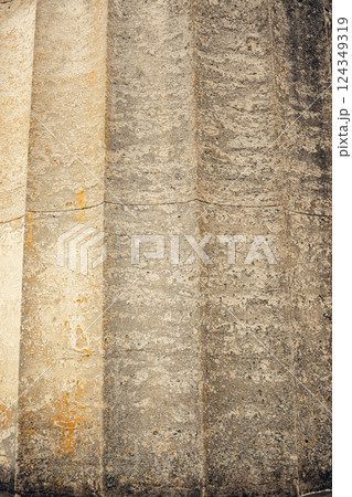 Old stone column showcasing vertical grooves and a rough, weathered texture. The aged surface and Old stone column showcasing vertical grooves and a rough, weathered texture. The aged surface and 124349319