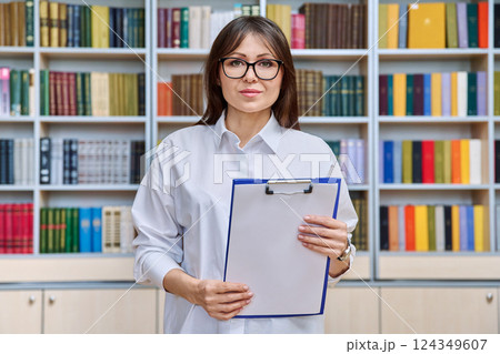 Portrait serious middle aged woman with clipboard inside library office 124349607