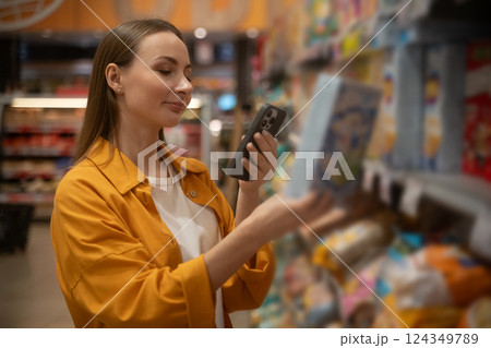 Woman scans cornflakes in grocery store while shopping for breakfast options during weekday 124349789