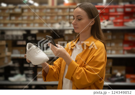 Woman uses smartphone to scan shoes in retail store for price and details 124349852