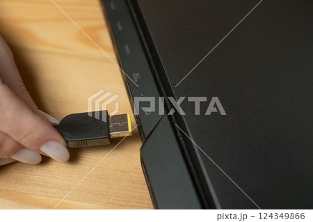 Connecting a charger to a laptop in a home office setting for efficient device charging 124349866