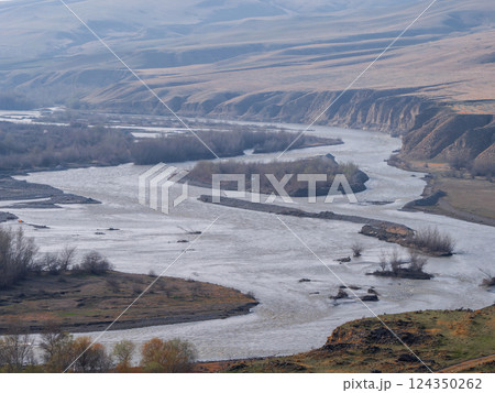 A river meanders through lush valleys, surrounded by distant hills and trees A river meanders through lush valleys, surrounded by distant hills and trees 124350262