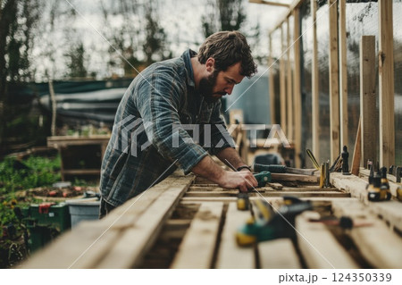 Carpenter working with wood boards and tools in outdoor workshop 124350339