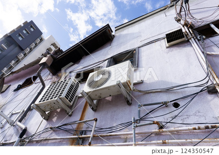 古い老朽化した建物に取り付けられたエアコンの室外機 124350547