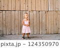 Little girl stands against the background of a wooden wall. High quality photo 124350970