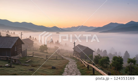 Serene mountain village at sunrise overlooking misty valley and majestic peaks 124353169