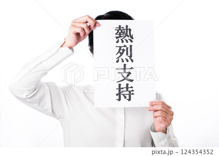 熱烈支持と書かれた紙を掲げアピールする白シャツの人物 124354352