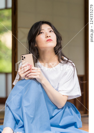 スマートフォンを片手に思い悩む若い女性 124355279