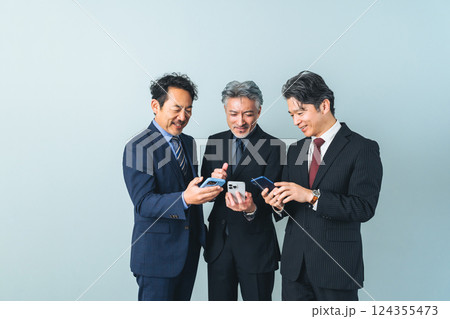 スマホの画面を見せ合うミドルエイジ男性ビジネスパーソンのグループ 124355473