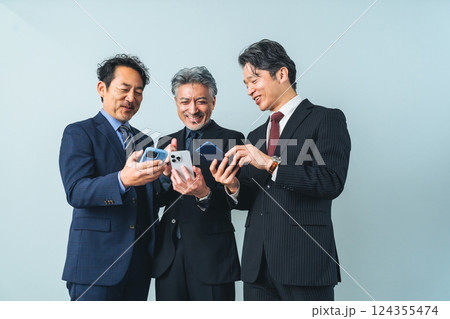 スマホの画面を見せ合うミドルエイジ男性ビジネスパーソンのグループ 124355474