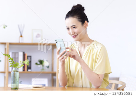 リビングでスマホを見ている女性 124356585