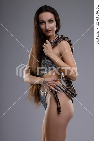 Woman poses gracefully with snake while showcasing elegant lingerie and beauty 124356601