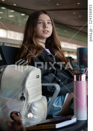Young girl waits at the airport for her plane's departure announcement Young girl waits at the airport for her plane's departure announcement 124356955