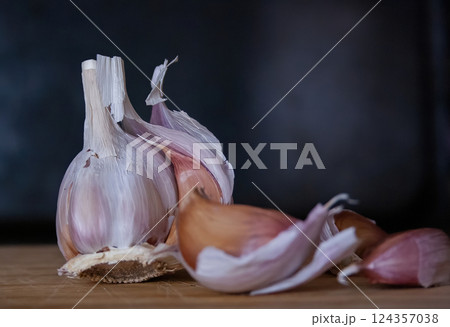 Garlic head and cloves on a wooden board with black background 124357038
