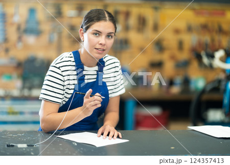Smiling repairwoman filling out orders in bike repair shop 124357413