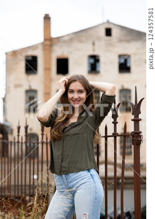 Woman posing near fence against abandoned building 124357581