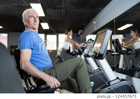 Elderly man exercising on exercise bike 124357673