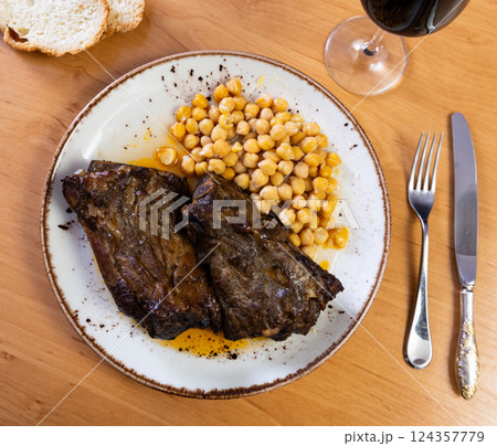 Roast whole pork knuckle served with chickpea on plate closeup 124357779