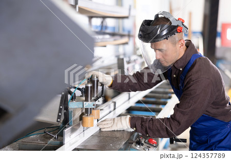 Workman cutting PVC profile on industrial machine in production workshop 124357789