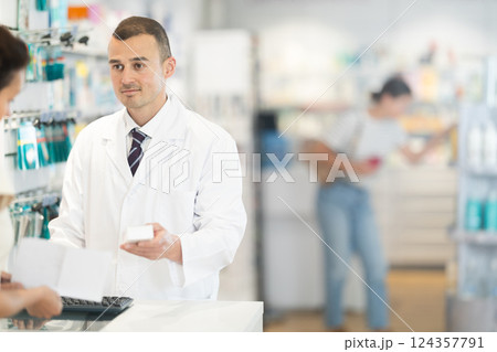 Male pharmacist giving prescription medicine to adult woman Male pharmacist giving prescription medicine to adult woman 124357791