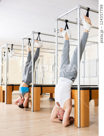Man hanging upside down on Pilates trapeze table in fitness studio 124357799