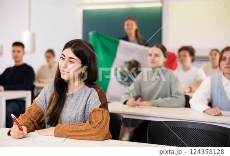 Female teacher tells her classmates about the country of Mexico, holding a flag in hands Female teacher tells her classmates about the country of Mexico, holding a flag in hands 124358128