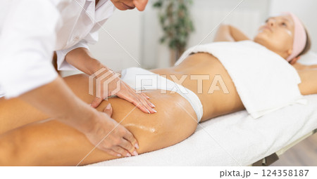Close-up of young woman getting thigh massage 124358187