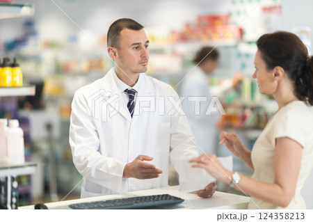 Male pharmacist consulting woman client about medicine indicated in her recipe 124358213