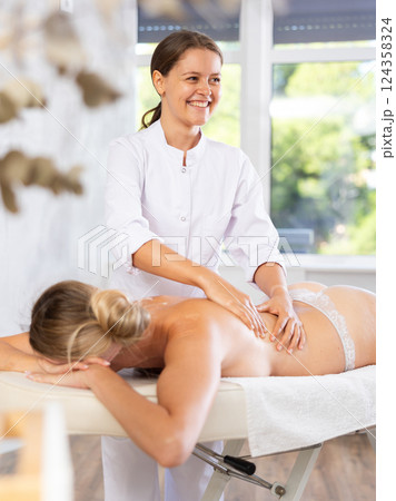 Young woman masseuse doing back massage Young woman masseuse doing back massage 124358324