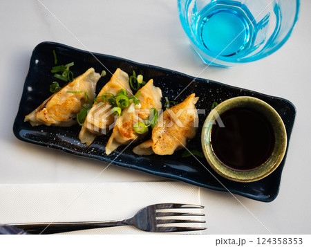 Grilled gyoza dumplings, bowl of soy sauce and chopsticks 124358353