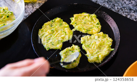 Zucchini pancakes cooked in frying pan 124358658