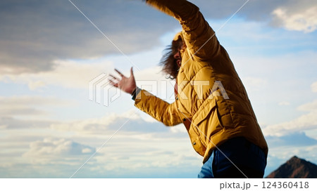 Hiker battling strong winds and cold weather tumbles over a cliff on the mountain top, dangerous risky place for trekking. Unprepared adventure seeker being foolish and tripping. Camera B. 124360418