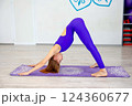 Woman practicing downward-facing dog yoga pose in a studio 124360677
