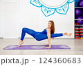 Flexible woman performing an advanced yoga arm balance pose  124360683