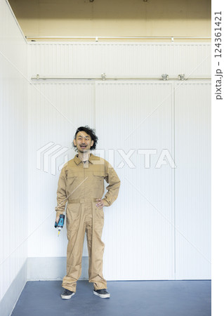 倉庫の中を歩くつなぎの男性 124361421