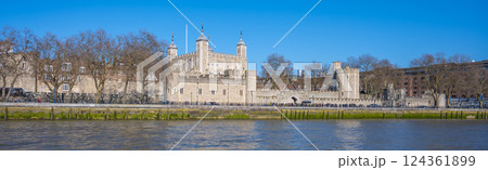 Tower Wharf showcases the historic Tower of London along the River Thames. Visitors admire the architecture and serene riverside view, enjoying a sunny, clear day in London. 124361899